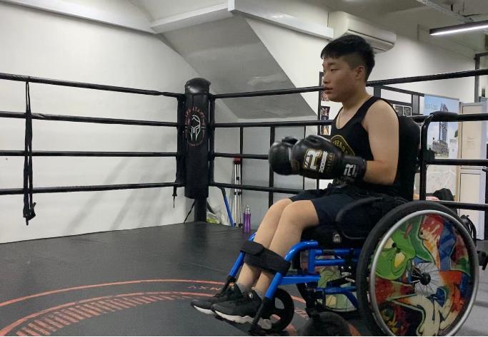 Photo shows Keith Tan wearing his boxing gloves in his wheelchair