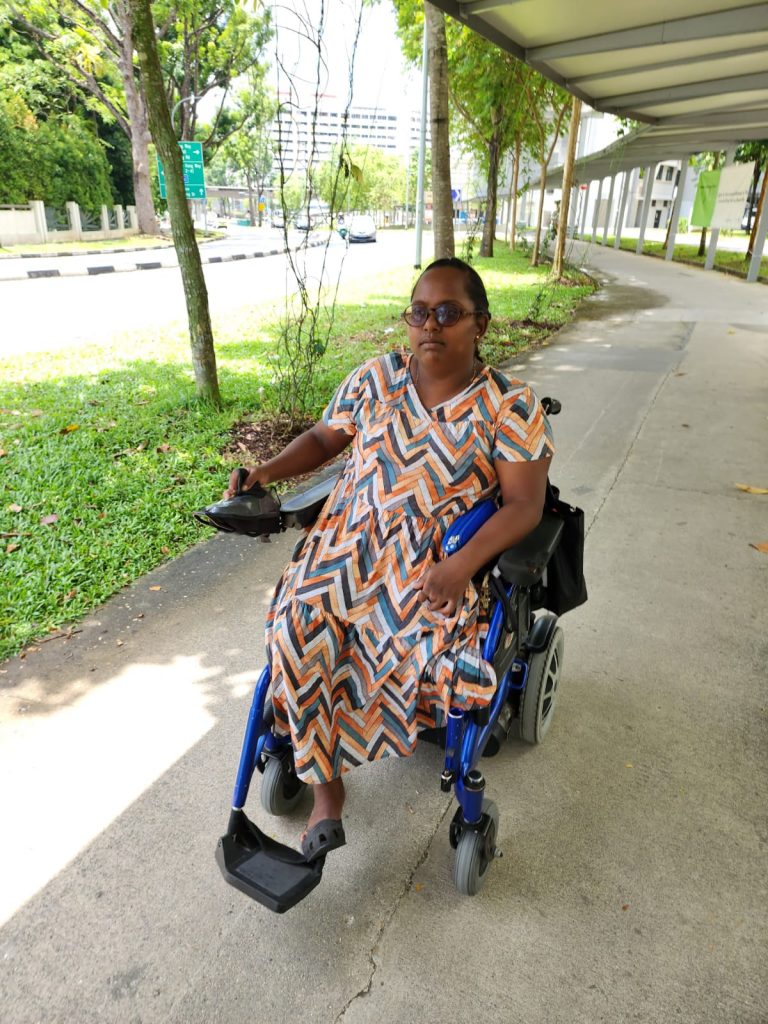 Image shows beneficiary Mary Sagaya travelling on her motorised wheelchair, which she purchased with aid from the Goh Chok Tong Enable Fund (GCTEF)
