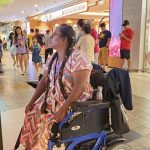 Image show beneficiary Mary Sagaya with her motorised wheelchair traveling confidently on her own